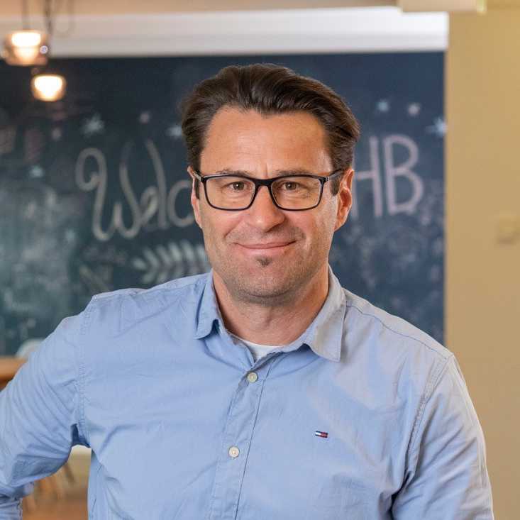 Portrait picture of a smiling caucasian man wearing glasses and a light blue dress shirt