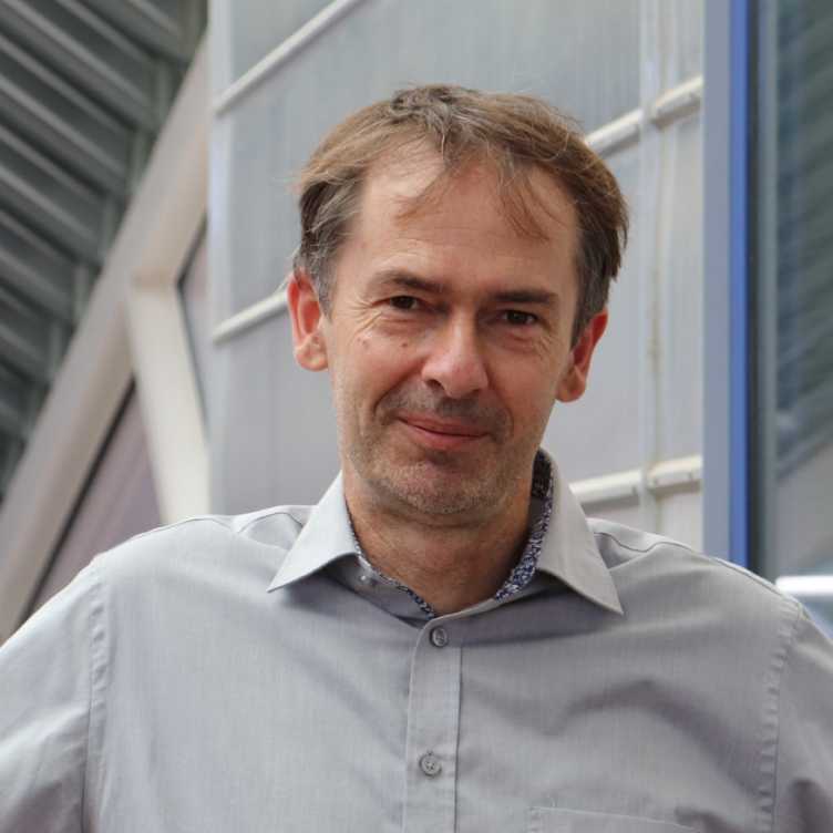 Headshot picture of a man wearing a light blue shirt